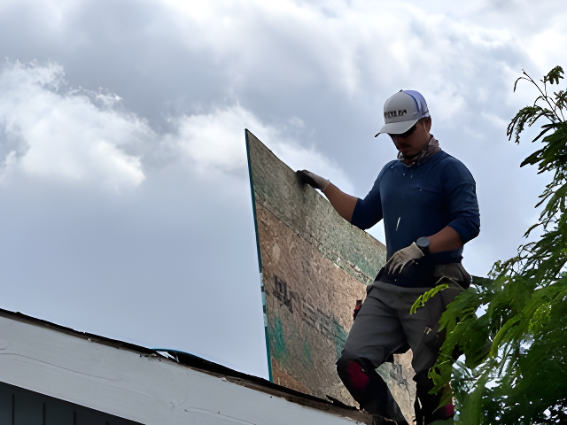 a man on a roof working on a piece of wood